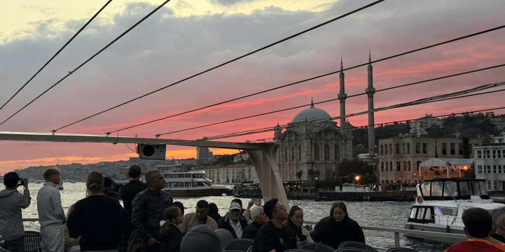 Guests enjoying sunset views on open deck during Bosphorus cruise in Istanbul